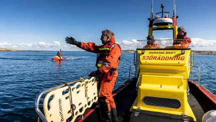 Frivillig sjöräddare står på en båt och pekar med hela handen